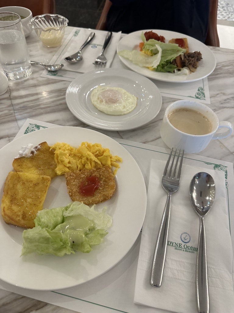 Breakfast plate with toast, scrambled eggs and salad, plus a fried egg and coffee, at Andamiro